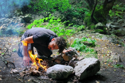man lighting fire in the firepit in forest 