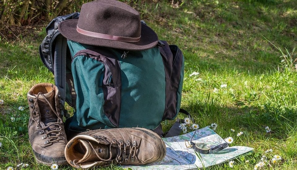 backpacking backpack with hiking shoes and map and hat on grass
