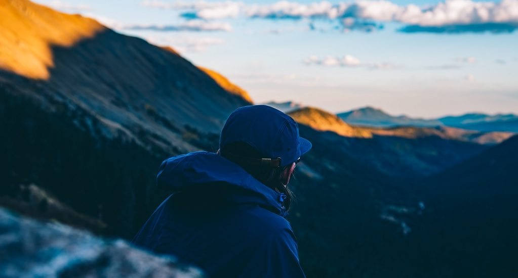 Man wearing rain jacket is gazing at mountains