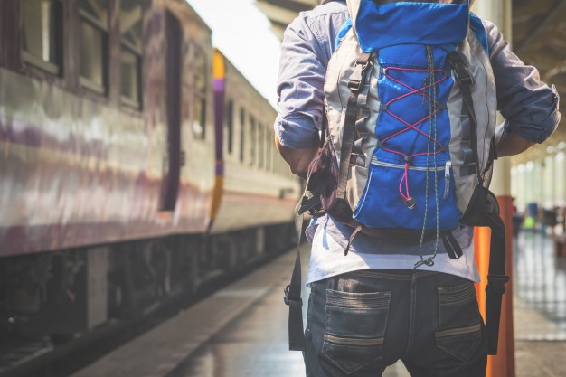 Man carrying ultralight backpack awaiting on railway platform
